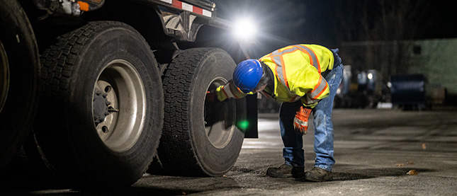 A employee checking the tiers on a Casella waste truck.