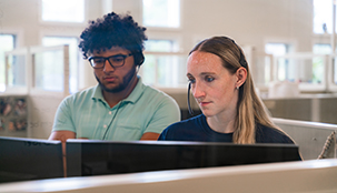 Two workers looking at the same computer screen in an office