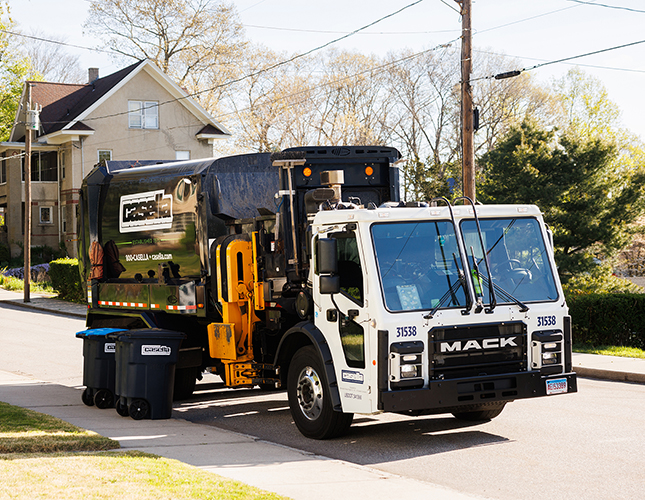 Casella waste truck picking up trash can on the safe of the residential road.