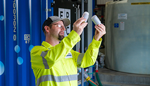 A worker holding up two sample containers and comparing them