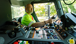 A driver in a Casella waste truck with the dashboard and control panel in the middle.