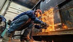 A worker welding a dumpster.